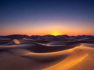 Shifting desert sand dunes under deep cloudless sky during sunrise
